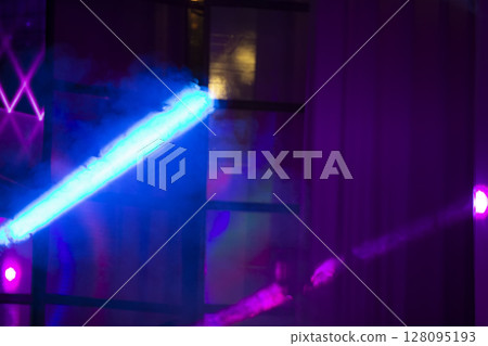 Multicolored rays of light from a stage spotlight on a blue background. 128095193