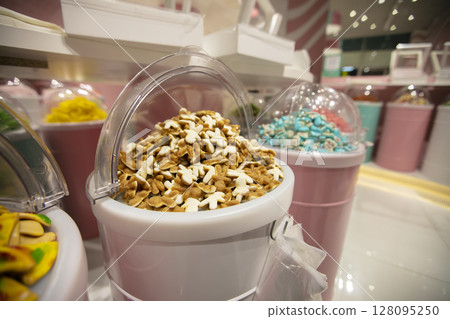 Jelly candies in containers in a store. Large selection of sweets in different colors. Sale of sweets. 128095250