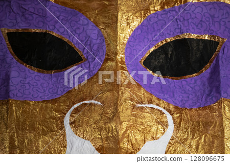 Golden theater mask with eye slits close-up. 128096675