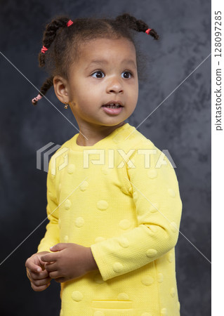 A little African American girl in a yellow dress looks surprised. A little African American girl in a yellow dress looks surprised. 128097285