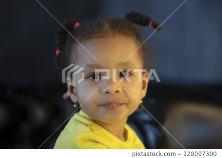 Little African American girl of two years old with pigtails looks at the camera. Little African American girl of two years old with pigtails looks at the camera. 128097300