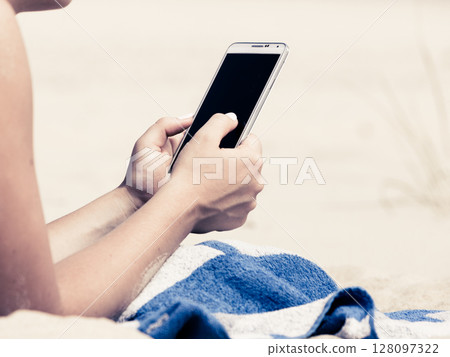 Woman on beach texting on smartphone. Woman on beach texting on smartphone. 128097322