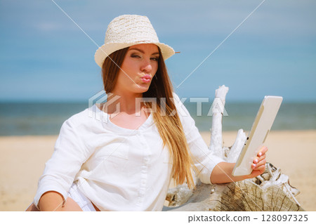 Woman with tablet pc computer on beach Woman with tablet pc computer on beach 128097325