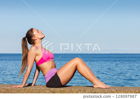 Woman doing sports exercises outdoors by seaside 128097987