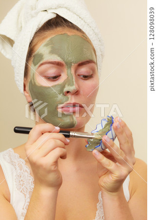 Woman applying with brush clay mud mask to her face Woman applying with brush clay mud mask to her face 128098039