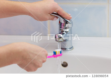 Hand holding toothbrush in bathroom Hand holding toothbrush in bathroom 128098054
