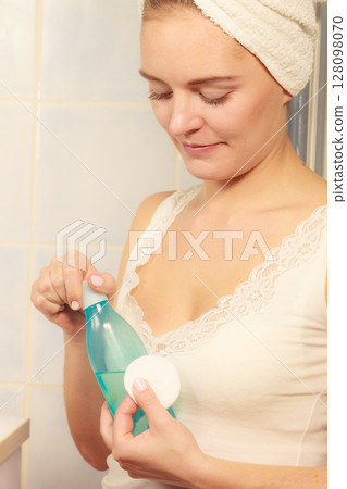 Woman with cotton swab cleaning her skin. 128098070