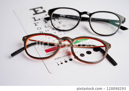 Glasses on eye exam chart to test eyesight accuracy of reading. 128098293