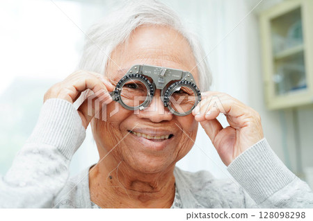 Asian senior woman wearing ophthalmic vision eye test and using optical trial frame. Asian senior woman wearing ophthalmic vision eye test and using optical trial frame. 128098298