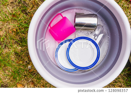 Washing up dishes in bowl, camping outdoor 128098357