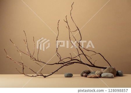 An intricately entwined branches and smooth stones against a beige background. 128098857