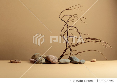 An intricately entwined branches and smooth stones against a beige background. 128098860