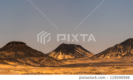 Ash-covered hills in Egypt's Black Desert under a clear sky, scenic and remote landscape. Volcanic	 128098986