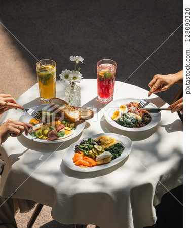 People having assorted breakfast dishes and drinks 128099320