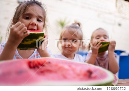 Joyful kids enjoying juicy watermelon on a sunny afternoon Joyful kids enjoying juicy watermelon on a sunny afternoon 128099722