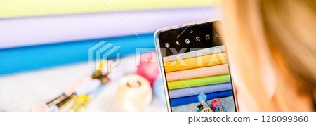 A woman takes a photo on a smartphone. Accessories for hobby embroidery knitting 128099860