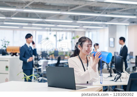 Young woman speaking through a megaphone in an office Young woman speaking through a megaphone in an office 128100302