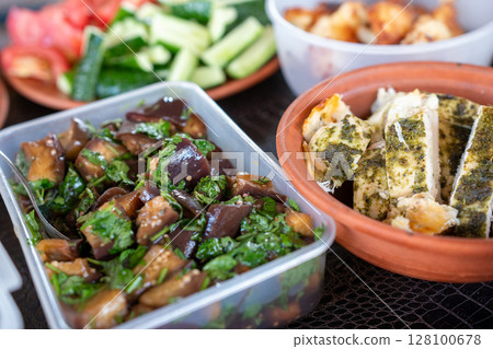 Eggplant Salad Chicken Tomatoes Appetizers arranged indoors for lunch or dinner on table for meal. 128100678