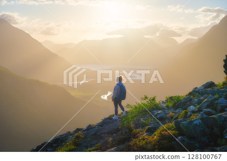 A young athletic girl standing on a rock with a backpack. Norway. 128100767