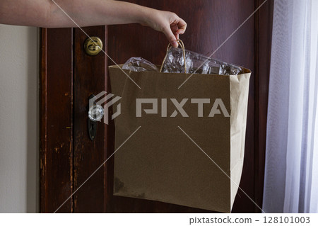Eco Recycling Paper Bag in Hand Against Old Wooden Door Background 128101003
