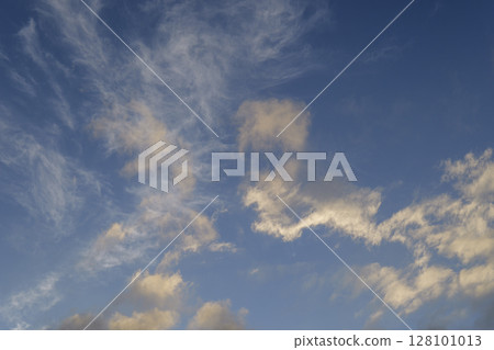 Light wispy cloud formations scattered over vibrant blue sky for clean sky background 128101013