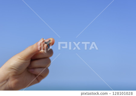 Close up of hand holding shark tooth against sandy Gulf coast background with sea horizon Close up of hand holding shark tooth against sandy Gulf coast background with sea horizon 128101028