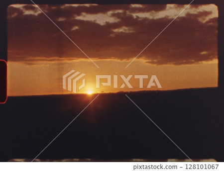 8 mm film - warm orange and red colors dominate the six separate shots of a setting sun, with silhouettes of landscapes and urban structures visible in the foreground 128101067