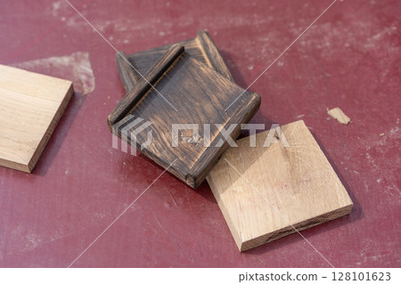Three wooden blocks rest on a reddish surface two are dark brown with edge grooves suggesting assembly use 128101623