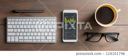 A modern workspace setup featuring a smartphone and coffee on a wooden desk. A modern workspace setup featuring a smartphone and coffee on a wooden desk. 128101746