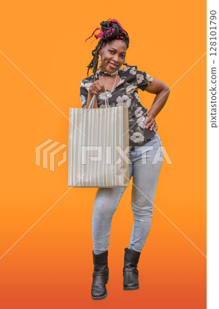 Black Woman Shopping with Striped Bag Orange Background Black Woman Shopping with Striped Bag Orange Background 128101790