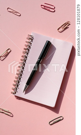 A black pen on a pink notebook with paperclips, ideal for writing or note-taking. A black pen on a pink notebook with paperclips, ideal for writing or note-taking. 128101879