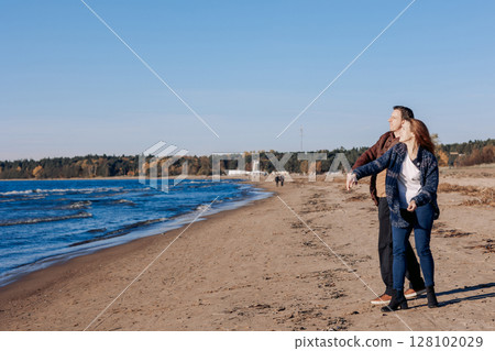 Young carefree couple in love throwing pebbles, shells, stones into sea outdoors. Fun family game together. High quality photo Young carefree couple in love throwing pebbles, shells, stones into sea outdoors. Fun family game together. High quality photo 128102029
