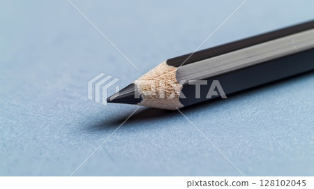 Black pencil on blue paper. Simple setup for drawing or school themes, perfect for art or education designs. Ideal for creative or minimalist visuals. 128102045