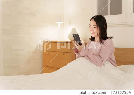 一位女士半夜看著她的智慧型手機 一位女士半夜看著她的智慧型手機 128102599