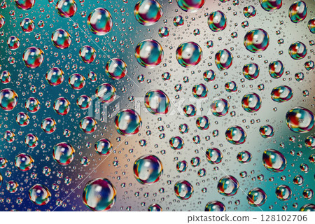 Colorful water drops on glass surface creating abstract macro pattern 128102706