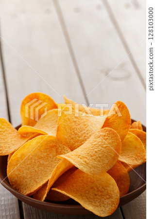 Crispy Potato Chips in Clay Bowl on Rustic Table Crispy Potato Chips in Clay Bowl on Rustic Table 128103000