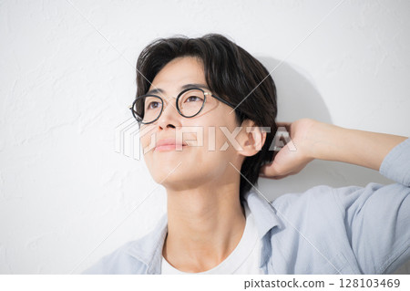 Close-up of a refreshing man wearing glasses, smiling and looking up 128103469