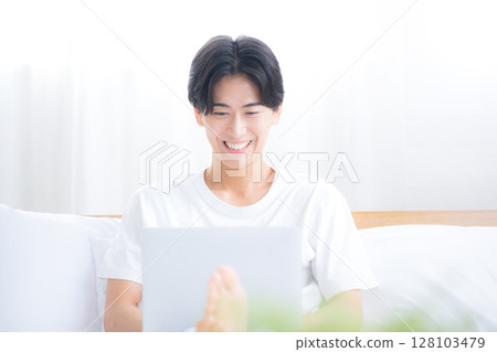 A man using a computer in bed, front view of a freelancer or busy office worker A man using a computer in bed, front view of a freelancer or busy office worker 128103479