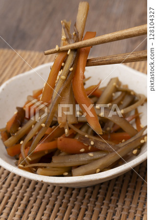 Pick up the kinpira burdock root served in a small bowl with chopsticks Pick up the kinpira burdock root served in a small bowl with chopsticks 128104327