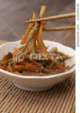 用筷子夾起盛在小碗裡的金平牛蒡根 128104328