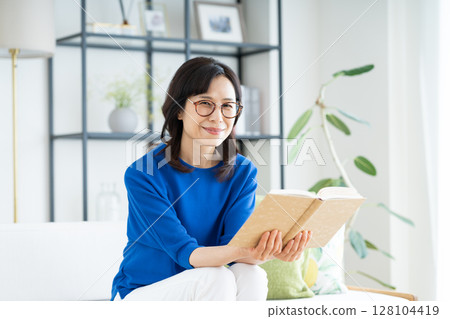 Middle-aged woman reading in the living room Middle-aged woman reading in the living room 128104419