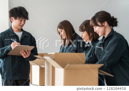 A worker of a transportation, logistics, courier, distribution, delivery, or delivery company packing packages into cardboard boxes 128104458