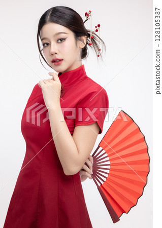 Portrait of joyful beauty Asian woman in red Cheongsam Chinese traditional dress holding red fan isolated on white background for Chinese New Year festival content. 128105387
