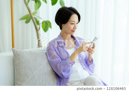 Middle-aged woman using a smartphone in a room 128106465