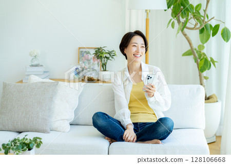 Middle-aged woman using a smartphone in a room Middle-aged woman using a smartphone in a room 128106668