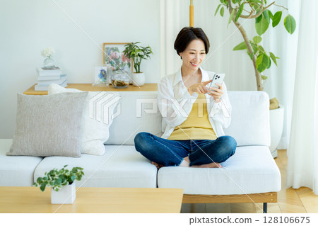 Middle-aged woman using a smartphone in a room Middle-aged woman using a smartphone in a room 128106675