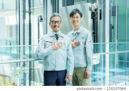Two workers standing in an office building with their hands on their chests. Photo courtesy of Sky Perfect Tokyo Media Center. Two workers standing in an office building with their hands on their chests. Photo courtesy of Sky Perfect Tokyo Media Center. 128107064