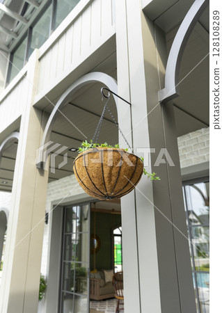 A flower in a hanging pot on the exterior wall. Planting flowers in hanging pots. Decorative floral decoration at home. A flower in a hanging pot on the exterior wall. Planting flowers in hanging pots. Decorative floral decoration at home. 128108289