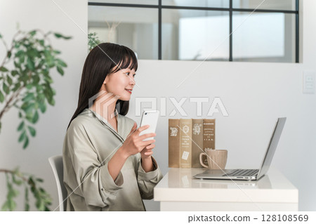 Young Asian woman working at home or office using smartphone 128108569