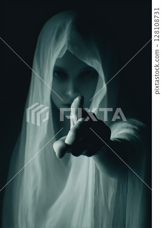 Ghostly figure in white veil points finger at viewer, mysterious and eerie atmosphere Ghostly figure in white veil points finger at viewer, mysterious and eerie atmosphere 128108731